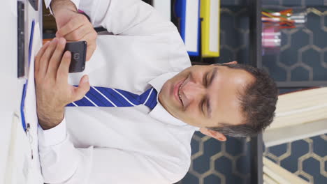 Vertical-video-of-Happy-businessman-using-phone-laughing.